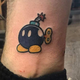 A person with a Bob-Omb tattoo poses for a photograph in a studio.